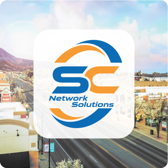 SC Network Solutions logo over a Cedar City main-street scene, used for a blog post on rural cyber threats and small business security.