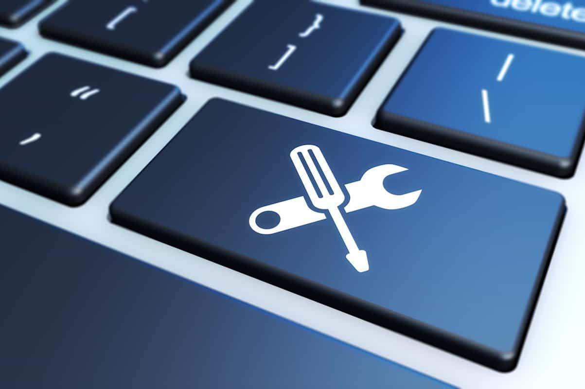 Close-up of a computer keyboard with a blue key featuring a screwdriver and wrench icon, symbolizing IT support and technical services.